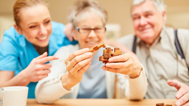 Memory care residents playing with some sort of wooden block puzzle